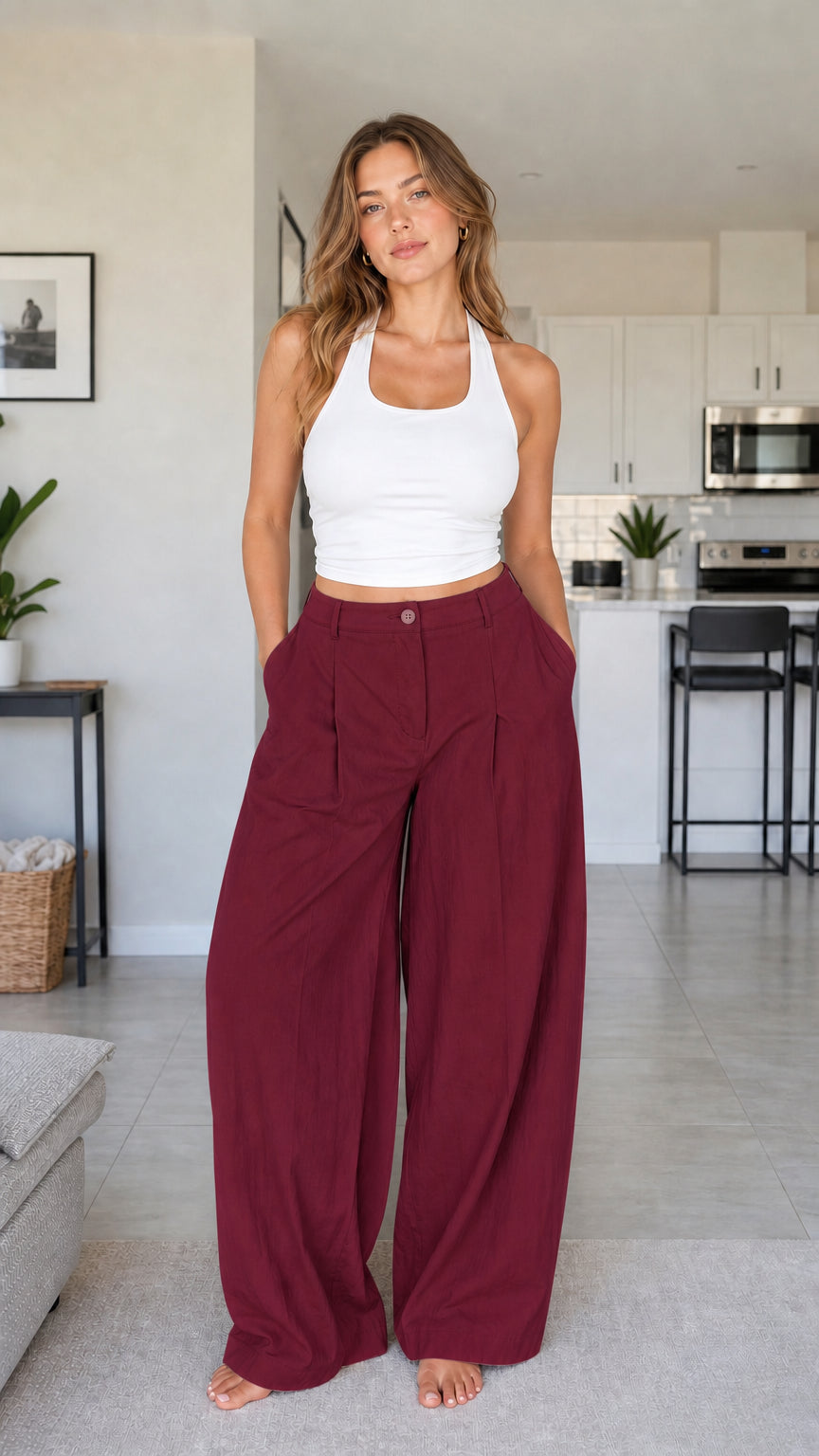 Full front view of model wearing burgundy wine red high waisted pleated wide leg trousers