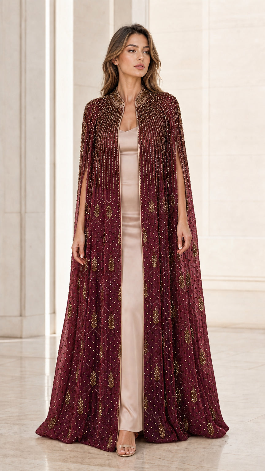 Model wearing burgundy red floor-length beaded cape evening gown