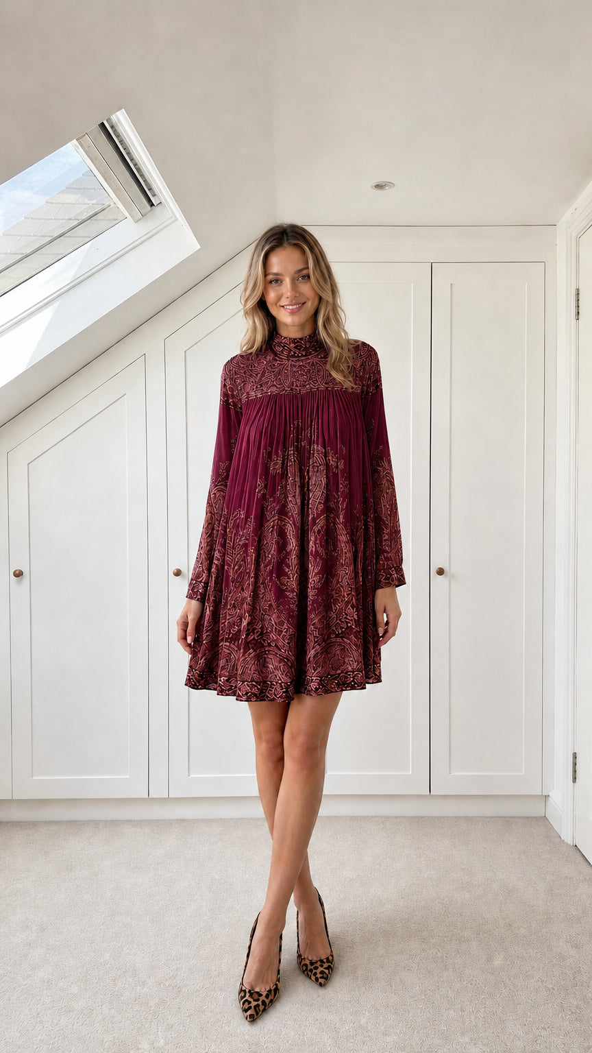 Model wearing burgundy wine paisley pleated high-neck mini dress