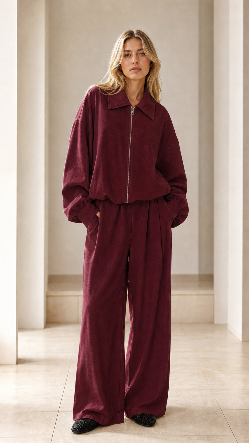Front view of woman wearing burgundy matching zip jacket and wide-leg pants set