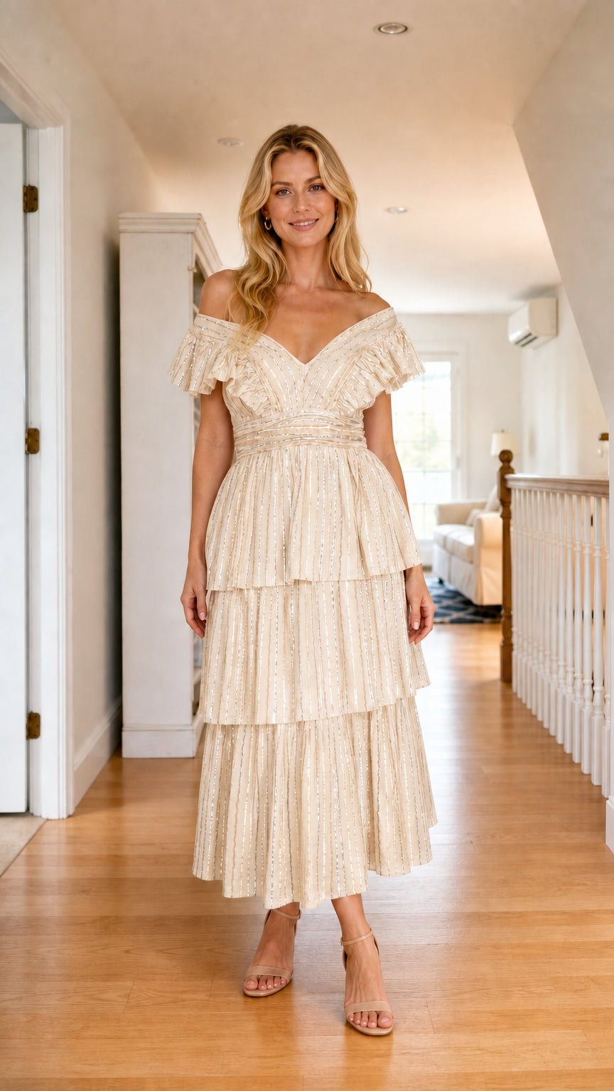 Front view of model wearing champagne off-shoulder ruffle tiered sequin midi dress