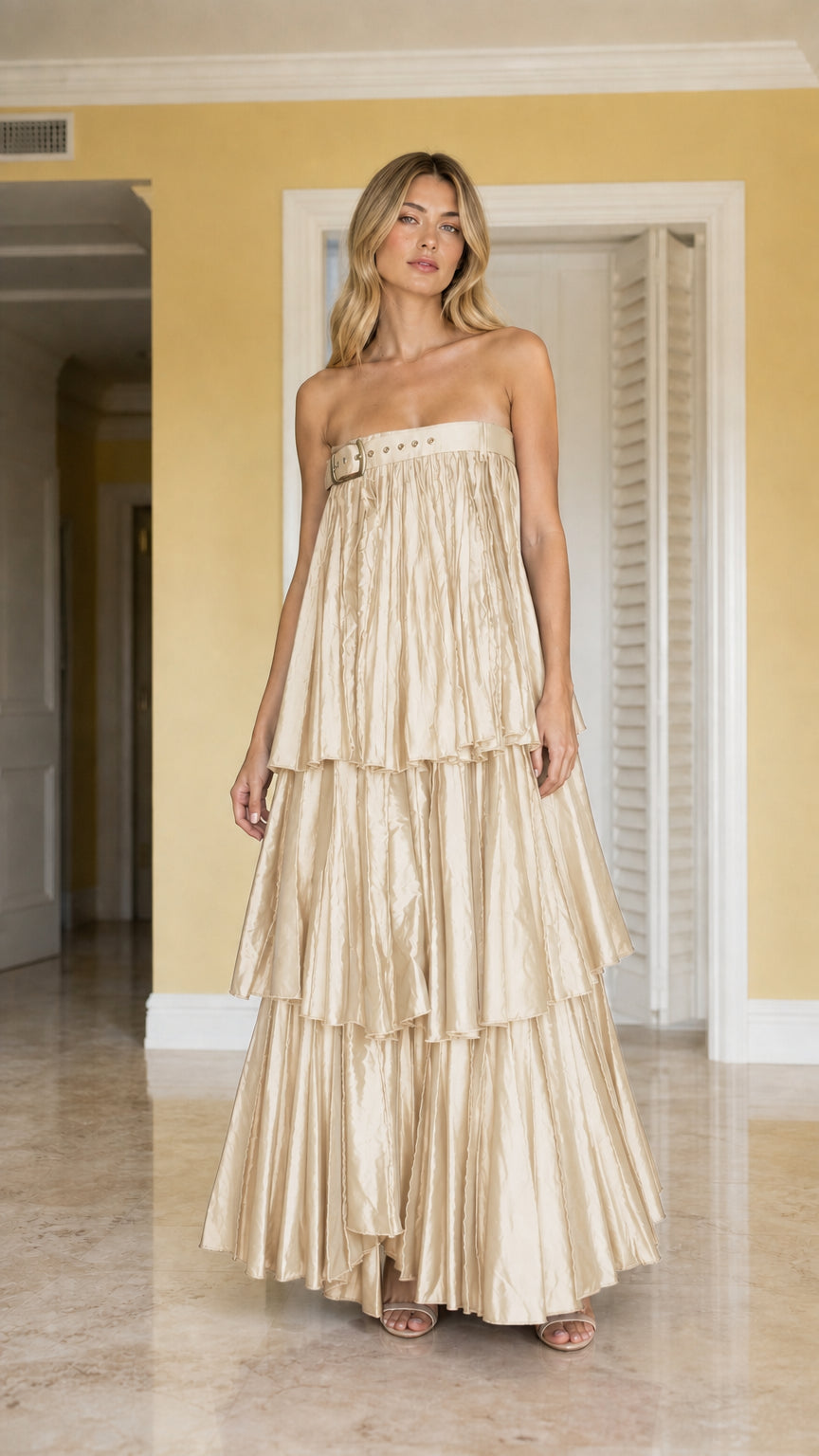 Front view of model wearing champagne gold strapless tiered pleated maxi dress