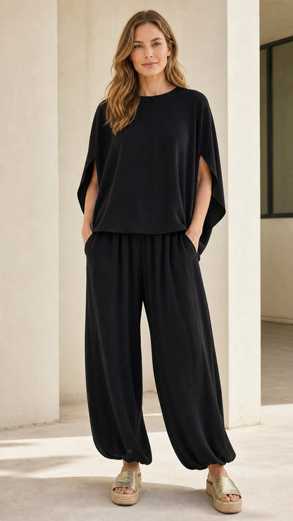 Front view of woman wearing black two-piece set with split-sleeve top and cinched pants