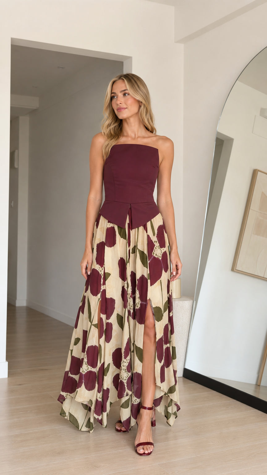 Front view of model wearing burgundy strapless floral maxi dress with high slit