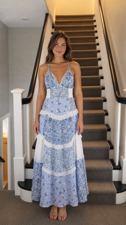 Front view of woman wearing blue floral tiered maxi dress on stairs