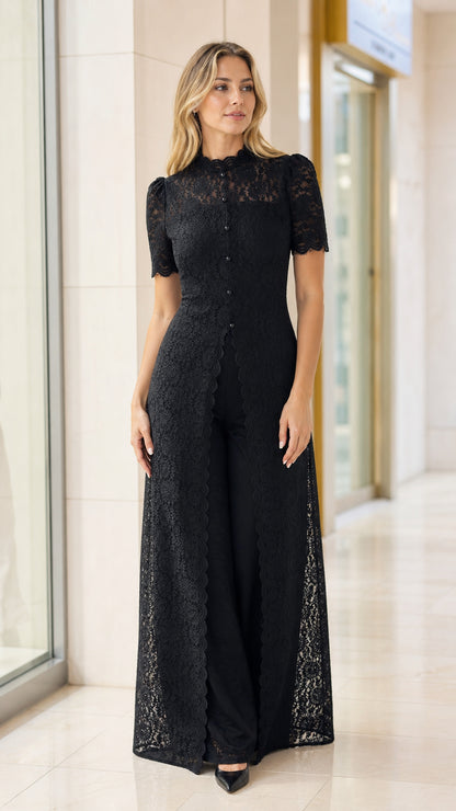 Front view of model wearing black high neck floral lace duster pantsuit