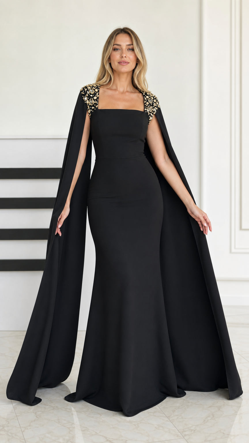 Front view of black mermaid evening gown with embellished shoulders and long cape sleeves