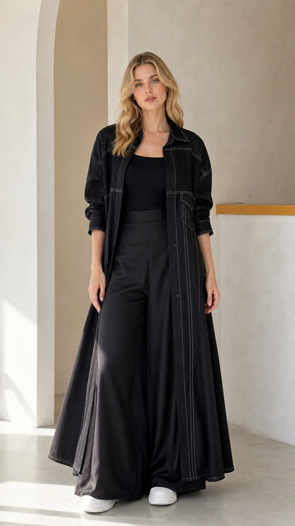 Front full view of woman wearing Black contrast stitch maxi duster coat and wide-leg trousers