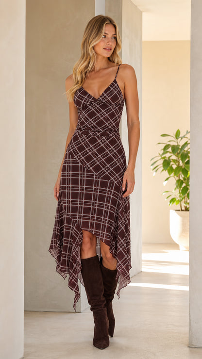 Front view of woman wearing brown plaid asymmetrical cami midi dress with boots