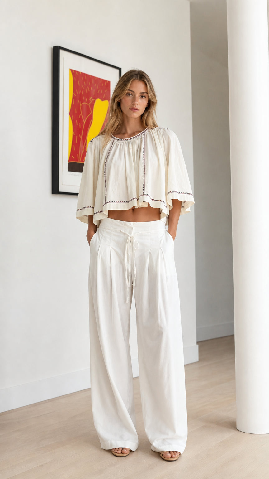 Front view of model wearing off-white embroidered cropped swing top and white wide-leg trousers