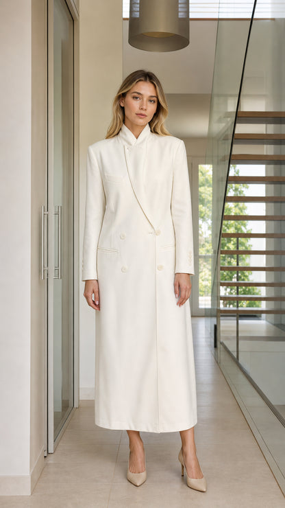 Front view of woman wearing ivory stand collar double-breasted maxi coat dress with pointed nude heels