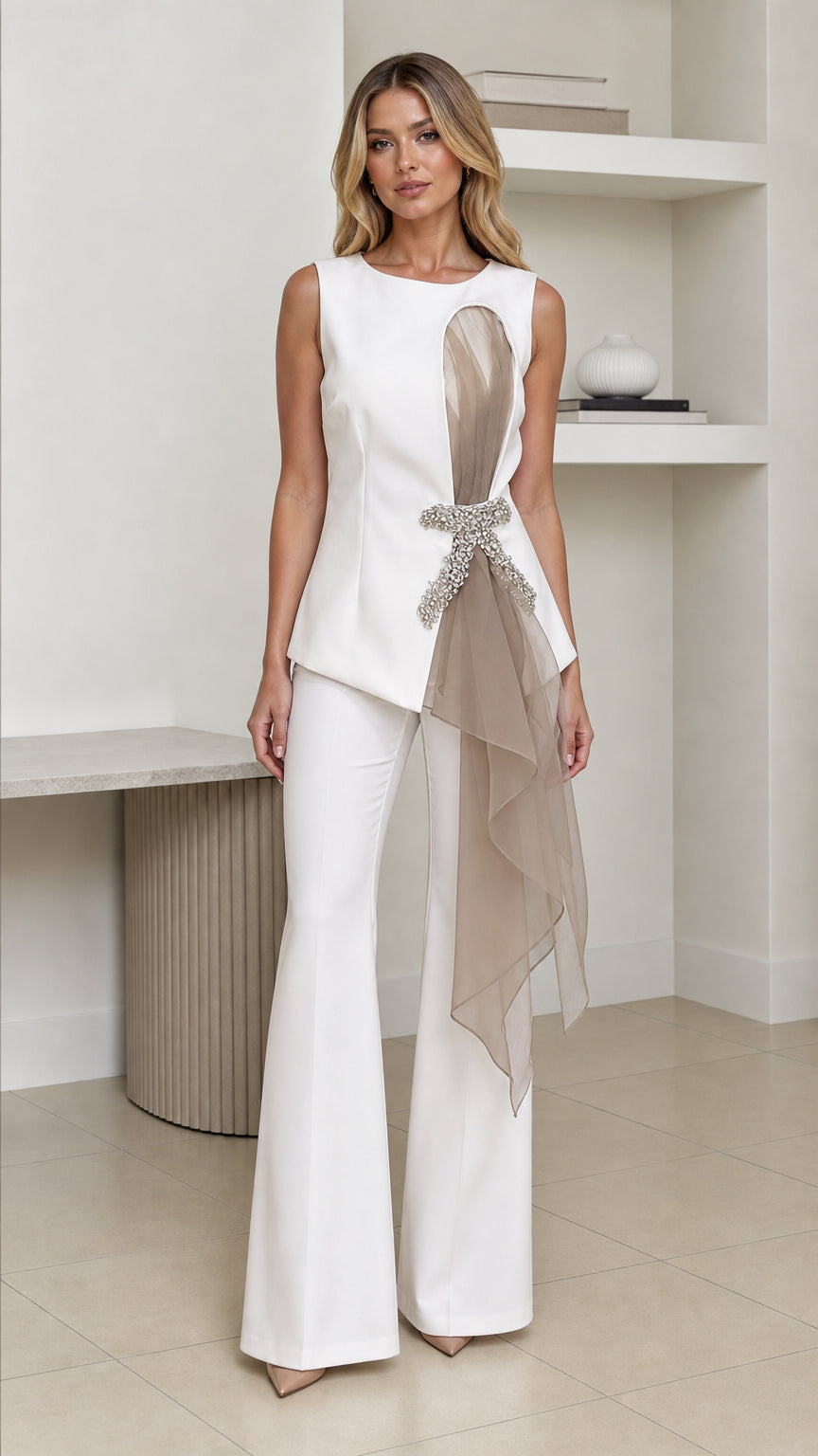 Front view of woman wearing white crystal embellished asymmetric top with white flared trousers