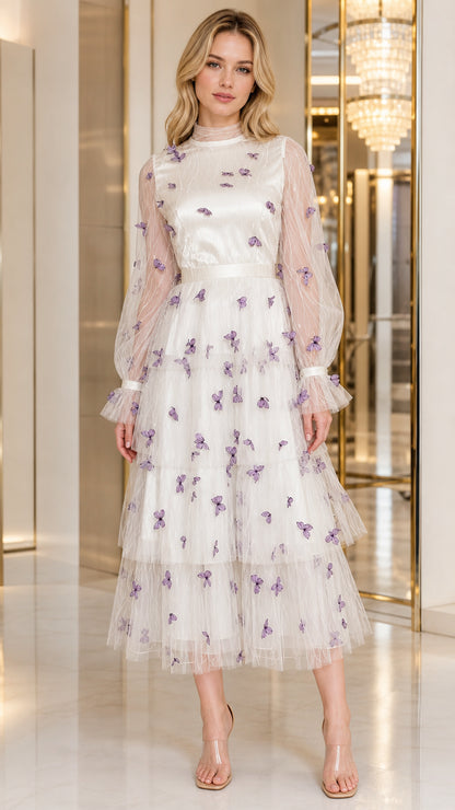 Front view of woman wearing ivory white tiered tulle midi dress with purple 3D butterflies