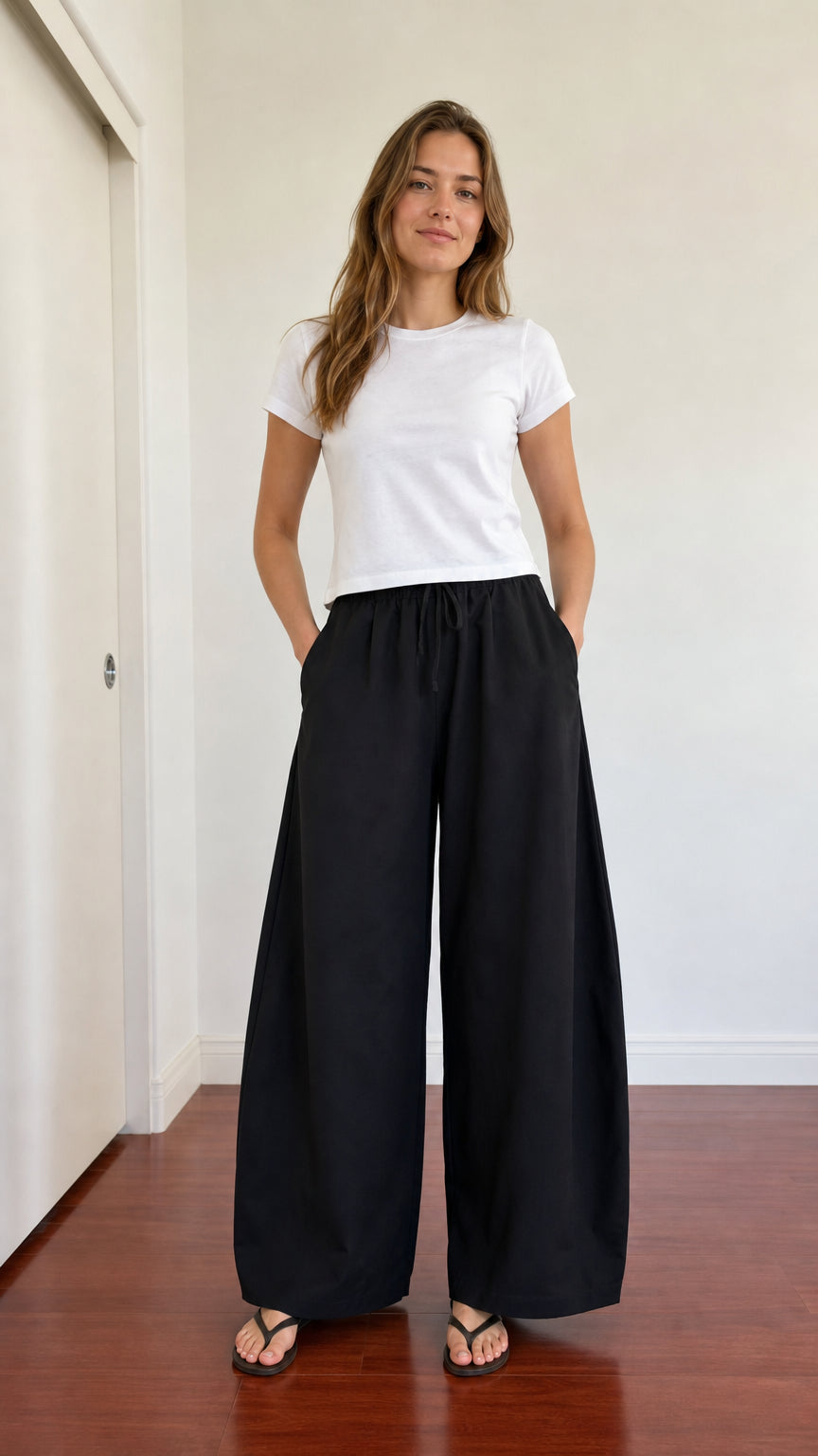 Front view of woman wearing black high waisted wide leg drawstring pants with white t-shirt