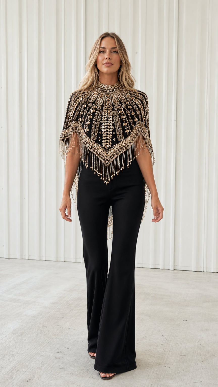 Front view of model wearing black beaded fringe evening capelet over black jumpsuit