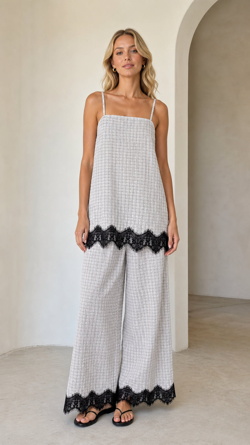 Model wearing white plaid cami top and wide leg pants set with black lace hem, front view