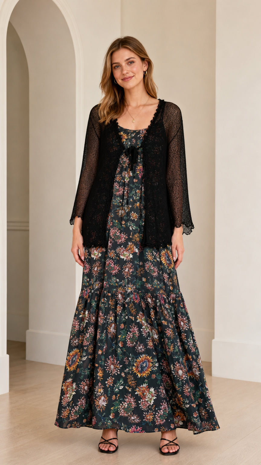 Front view of a woman wearing a black floral maxi dress with a sheer black cardigan overlay