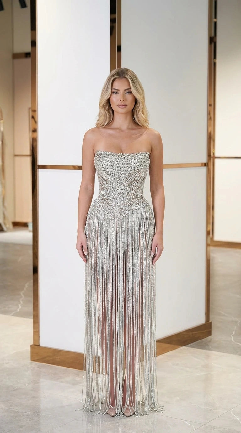 Front view of model wearing silver crystal embellished strapless fringe evening gown