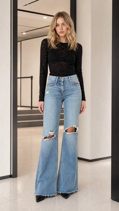 Model wearing black long-sleeve sheer lace top with light wash flare jeans, front view