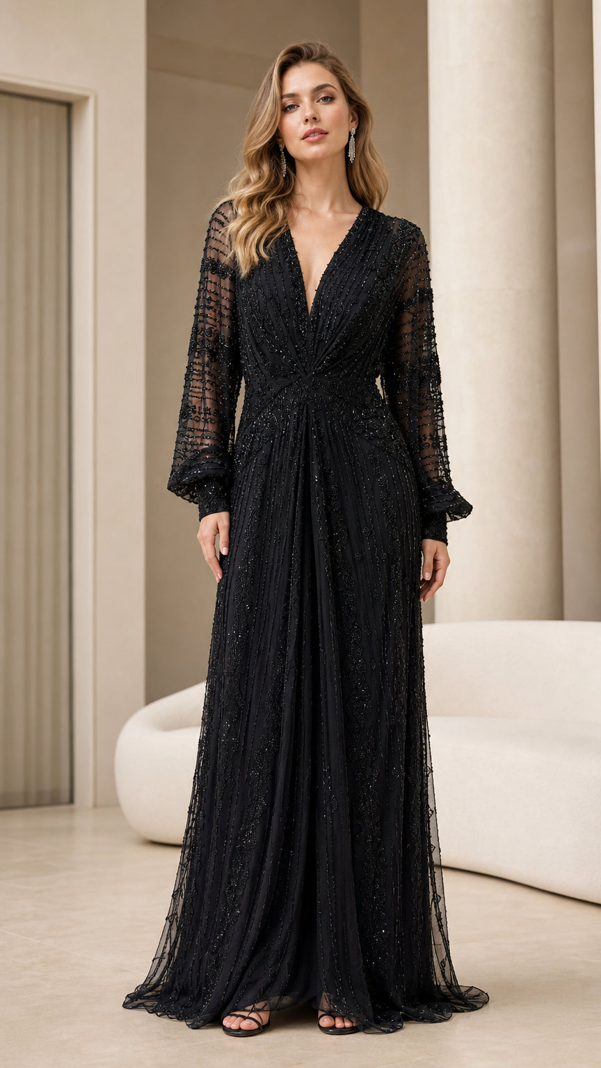Front view of woman wearing full-length black beaded evening gown with long sheer sleeves