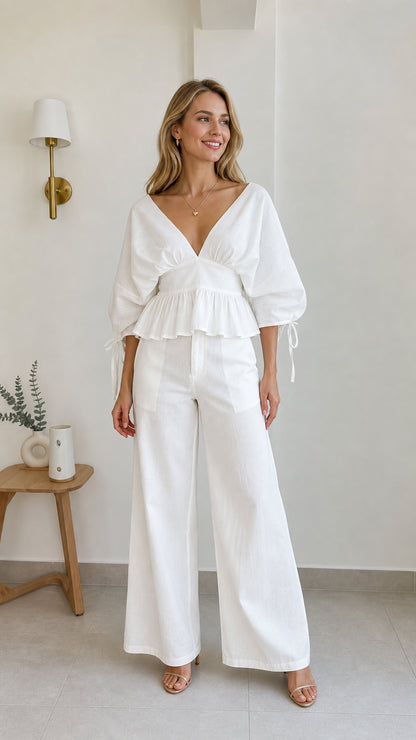 Front view of model wearing white V-neck peplum blouse and wide-leg pants set