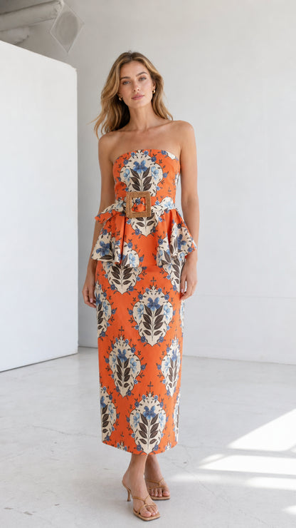 Full length front view of model wearing orange strapless floral midi dress with peplum belt