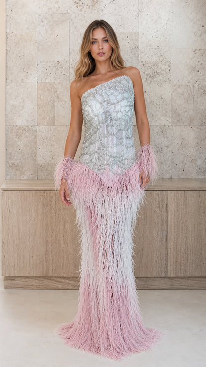 Front view of model wearing silver beaded one-shoulder gown with pink feather skirt