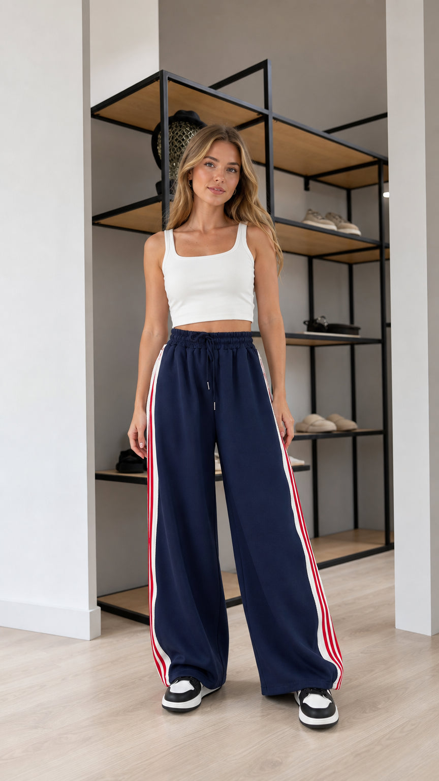 Front view of model wearing Navy Blue wide leg sweatpants with red and white side stripes