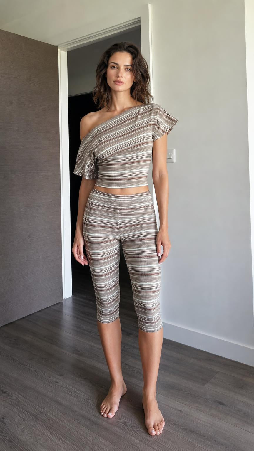 Front view of woman wearing brown striped one-shoulder crop top and capri leggings set