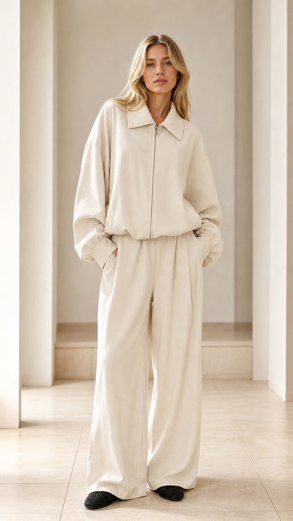 Front view of woman wearing cream zip-up collared jacket and wide-leg pleated pants set