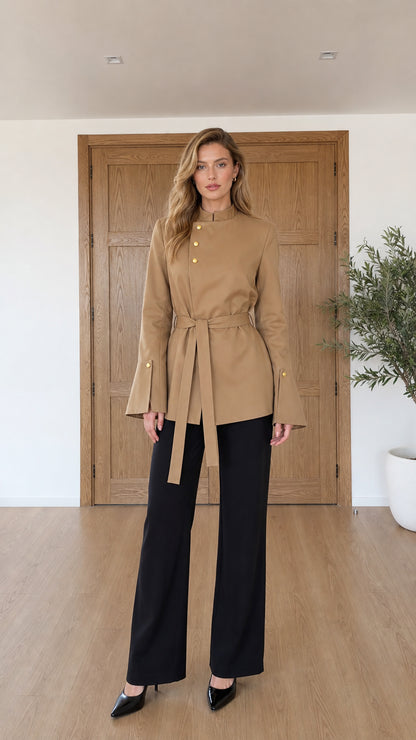Full front view of model wearing camel asymmetrical belted tunic jacket with black trousers