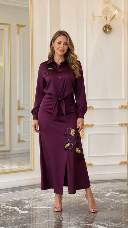 Woman wearing a burgundy satin-look embroidered maxi shirt dress with tie waist and front slit