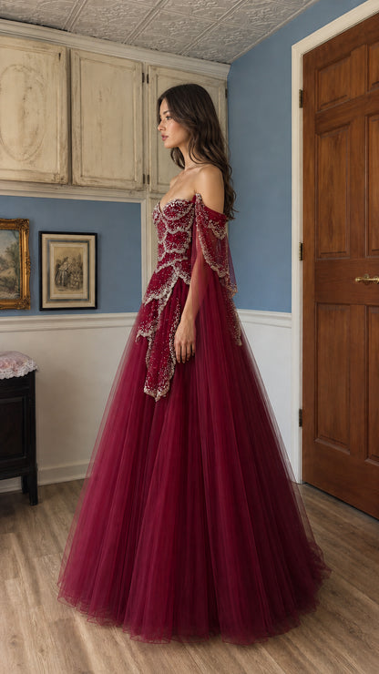Side profile view of burgundy evening gown with dramatic cape sleeves