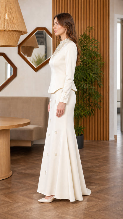 Side view of woman wearing ivory long sleeve beaded top and mermaid maxi skirt set