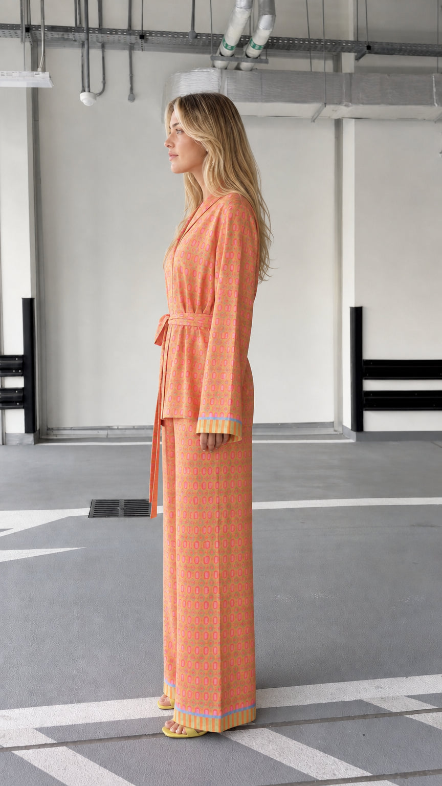 Woman wearing orange patterned two-piece lounge set, side view