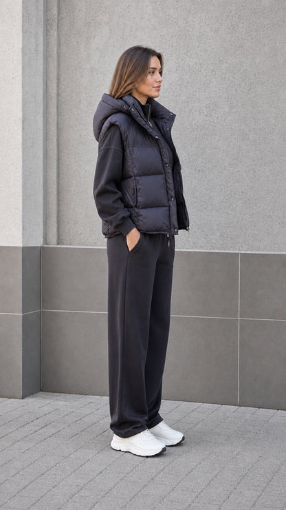 Side profile of woman in black hooded quilted vest and casual sweats