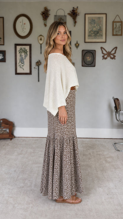 Model wearing white knit top and floral maxi skirt set, side view