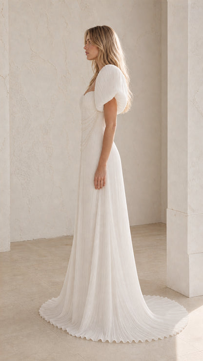 Side profile view of White pleated evening gown