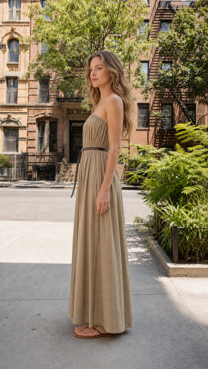 Side profile view of woman wearing khaki strapless pleated maxi dress