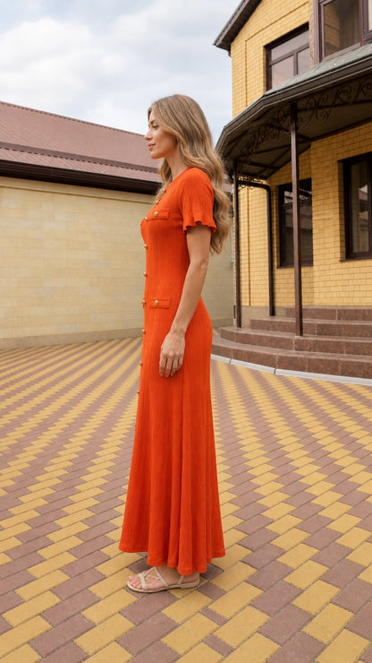 Side profile view of woman modeling orange ribbed knit maxi dress outdoors