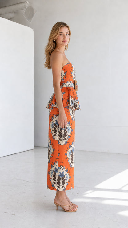 Side profile view of model in orange strapless floral peplum midi dress