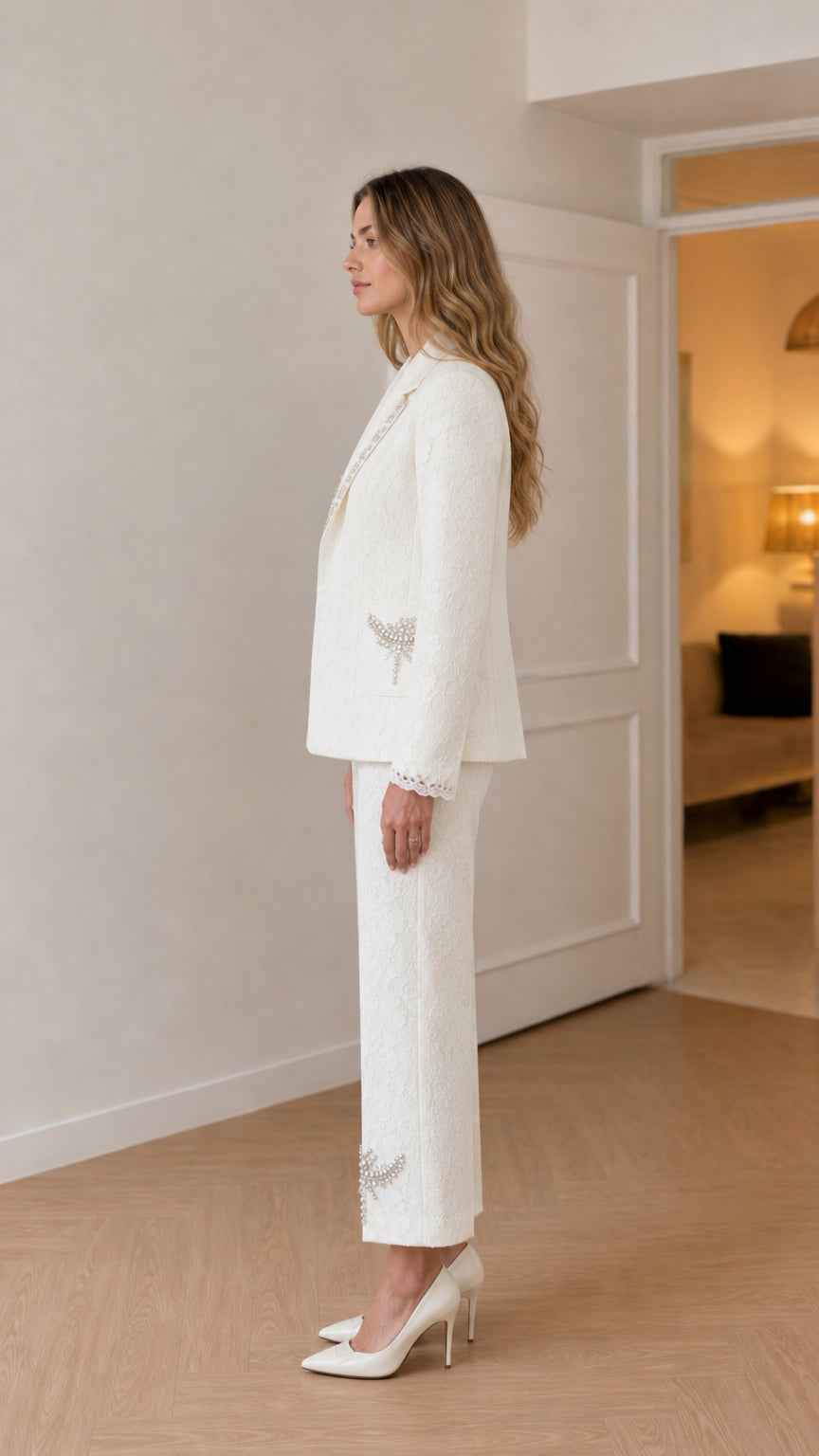 Side profile of model in white embellished blazer and straight-leg trousers
