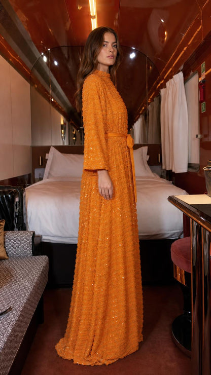 Side profile of orange textured sequin maxi dress