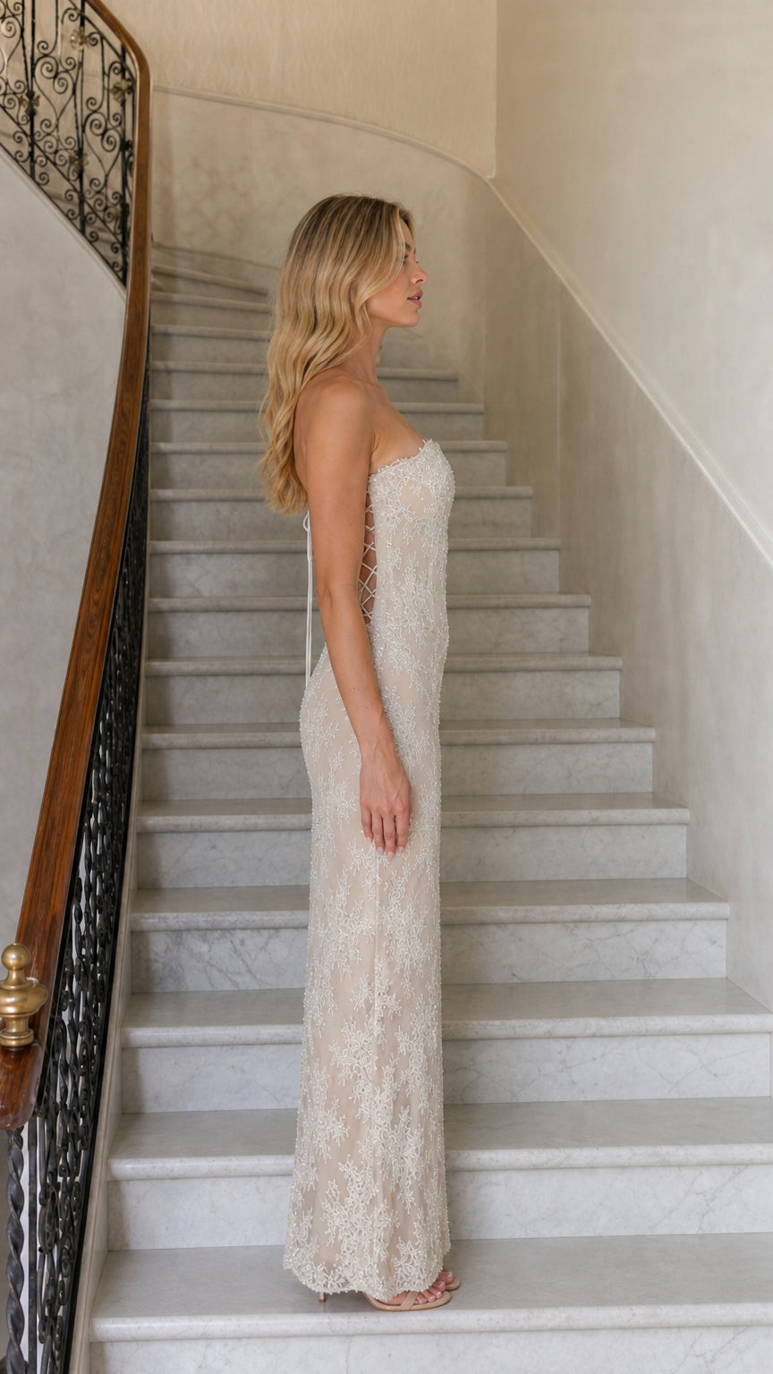 Side profile view of beige strapless lace gown
