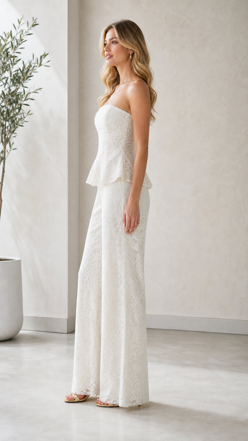 Model wearing white strapless lace peplum jumpsuit side view