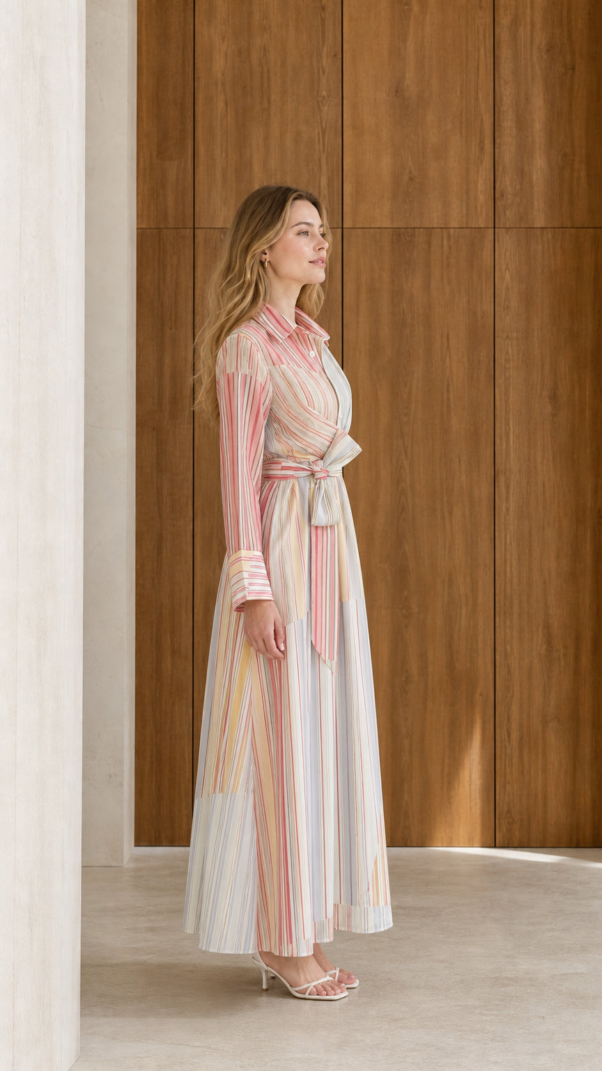 Side full-length view of model wearing pastel multi striped long sleeve maxi shirt dress