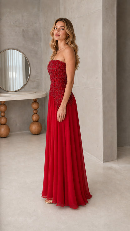 Side profile of model wearing strapless ruby red chiffon evening dress