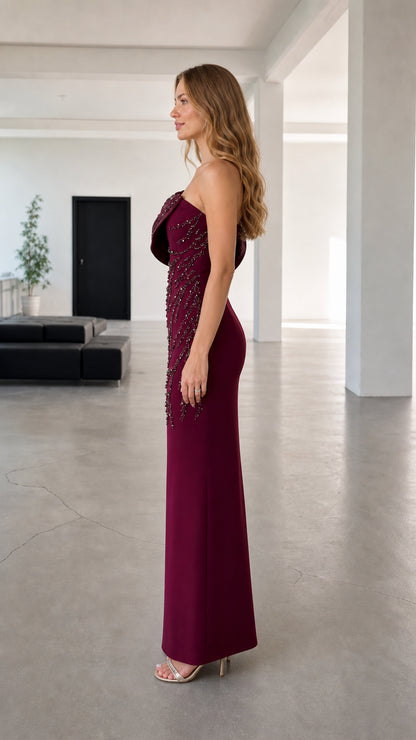 Side profile of woman in burgundy one-shoulder column formal dress