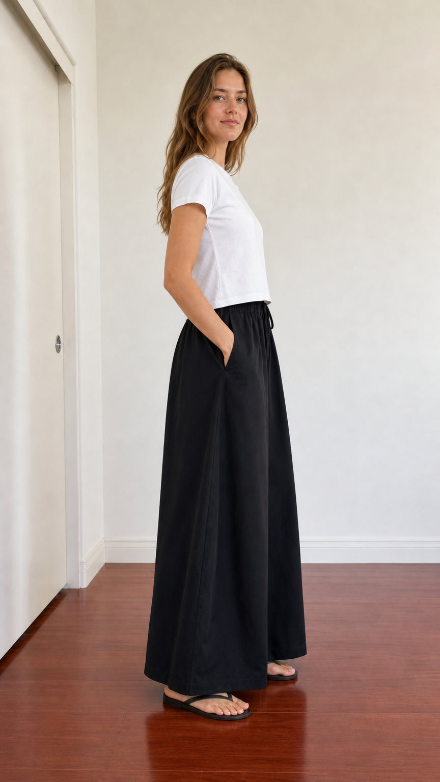 Side view of woman posing in relaxed black wide leg trousers with pockets