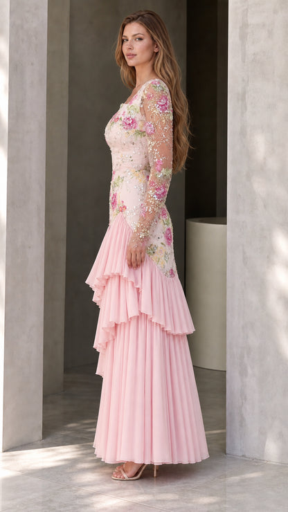 Side angle view of woman modeling pink long sleeve embroidered gown with pleated tiered hem